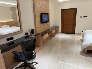 a bedroom with a desk and a bed and a chair at M Convention Eluru in Elūru +3 photos