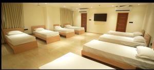 a room with four beds and a flat screen tv at M Convention Eluru in Elūru