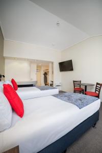 two beds in a hotel room with red pillows at Carnmore Hotel Lower Hutt in Lower Hutt