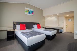 a hotel room with two beds and a desk at Carnmore Hotel Lower Hutt in Lower Hutt