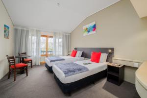 a hotel room with two beds and a table at Carnmore Hotel Lower Hutt in Lower Hutt