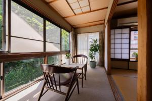 a room with a table and chairs and windows at guesthouse LAPPY in Ureshino