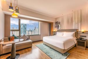a bedroom with a bed and a couch and a large window at Holiday Inn Shanghai Nanjing Road by IHG in Shanghai +184 photos
