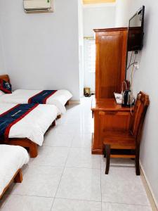 a row of beds in a room with a desk at Thiên Phúc Hotel in Mộc Châu
