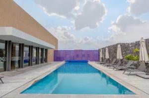 a pool with chairs and umbrellas next to a building at Loft en Zibata con Vista Alberca y Gym in La Cañada