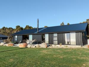 a house with a black roof and a yard at The Highland - Sunset Ridge in Ruatapu