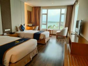 a hotel room with two beds and a television at Khách sạn Sài Gòn Vĩnh Long in Vĩnh Long