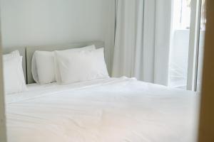 a white bed with white pillows and a window at BlackBrick Gardens in Cape Town