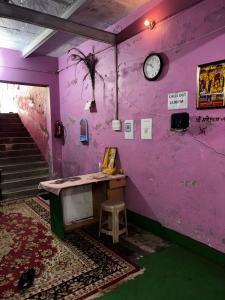 a room with a purple wall with a table and a clock at Brijwasi Seva Sadan in Mathura