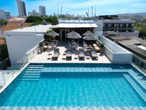 a pool on the roof of a building with chairs and umbrellas at GHL Arsenal Hotel in Cartagena de Indias