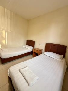 a bedroom with two beds and a window at HK Inn Hua Kiew Inn in Miri