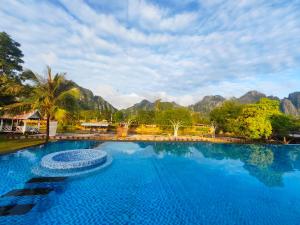 a large swimming pool with mountains in the background at Vangvieng Lina hotel in Vang Vieng