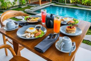 a table with breakfast food and drinks next to a pool at Kubu Tama Villa in Tegalalang