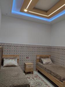 a room with two beds and a blue light at شقق يوسف للكراء in Gabès