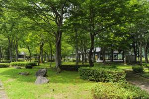 a park with trees and rocks in the grass at パークホテル九頭竜 in Ōno