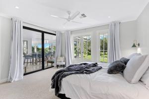 a white bedroom with a bed and a balcony at Whitepepper Cottage in Pokolbin +17 photos