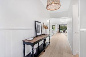 a hallway with white walls and a table in a room at Whitepepper Cottage in Pokolbin
