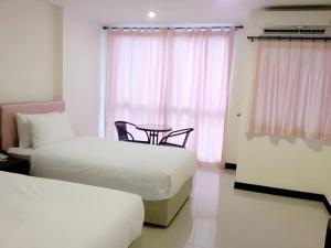 a room with two beds and a table and a window at The Capital Hotel in Roi Et +30 photos