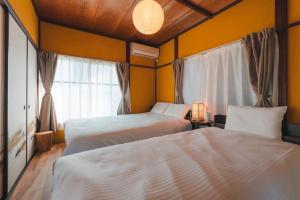 two beds in a room with yellow walls at Odawara Nautical Nook in Odawara
