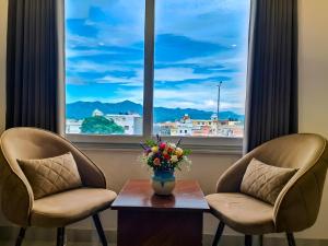 two chairs and a vase of flowers on a table in front of a window at Palm Bliss A Luxury Hotel in Haridwār +17 photos