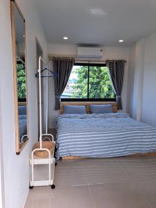 a bedroom with a bed and a large window at Kan Haven Homestay in Kanchanaburi City