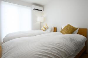 two white beds in a bedroom with a window at Villa UMMINA in Tahara