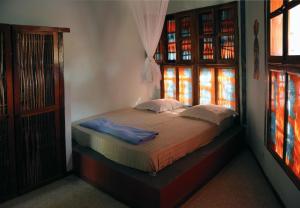 a small bed in a room with two windows at Fromager in Cap Skirring