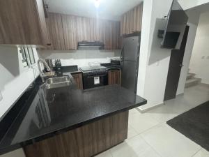 a kitchen with a black counter top and a refrigerator at TadeoHouse in Tijuana