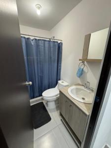a bathroom with a toilet and a sink with a blue shower curtain at TadeoHouse in Tijuana