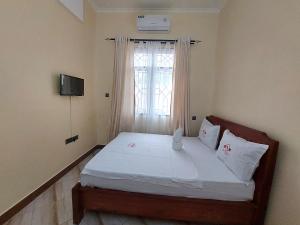 a bedroom with a bed with white sheets and a window at Nyerere Green Lodge in Kwangwazi
