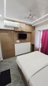a small room with a bed and a tv at Luxmi Hotel in Allahābād