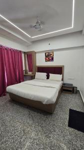 a bedroom with a large bed with red curtains at Luxmi Hotel in Allahābād