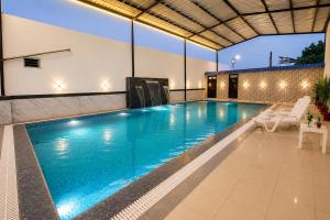 a swimming pool with chairs and a table and a building at Hotel Bhairav Bagh -100 Mtr from Celebration Mall in Udaipur