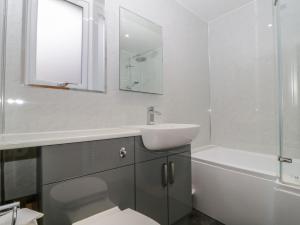 a white bathroom with a sink and a bath tub at High Spy in Keswick +11 photos