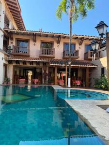 ein Swimmingpool vor einem Haus mit einer Palme in der Unterkunft Hotel Jacarandá Suites in Trinidad