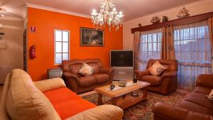 a living room with orange walls and leather furniture at Paradise House Calheta in Calheta