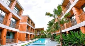 an apartment building with a swimming pool and palm trees at Riverton Hotel in Samut Songkhram