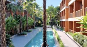 a swimming pool with a palm tree next to a building at Riverton Hotel in Samut Songkhram