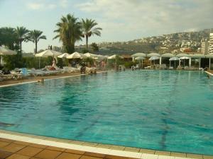 a large swimming pool with palm trees and umbrellas at Chalet 1BR 1BA with Beach&Pool&Tennis&Basketball in Jounieh