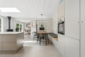 a kitchen with white cabinets and a wooden table at Luxury Retreat Surrounded By Nature in Rønde
