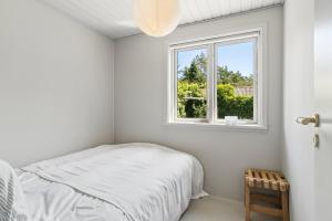 a white bedroom with a bed and a window at Luxury Retreat Surrounded By Nature in Rønde