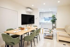 a dining room with a wooden table and green chairs at ぷにるんパーク in Nagoya