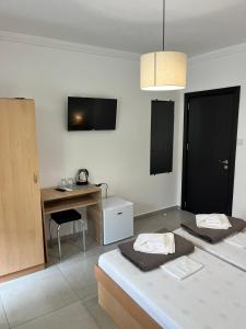 a room with two beds and a desk and a television at Kъща за гости Христина in Lozenets