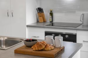 a wooden cutting board with croissants and a bowl of berries at Native Retreat - Tranquil Seaham Escape in Seaham