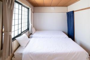 two beds in a small room with a window at c Furano A in Furano