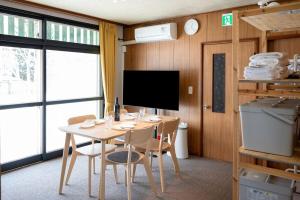 a dining room with a table and chairs and a tv at c Furano A in Furano
