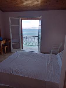 a bedroom with a bed and a view of the ocean at Corfu sunrise sea view apartments 100m from the beach in Benitses
