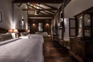 a bedroom with three beds and a couch in a room at Uthai Heritage Hotel in Ban Nong Nam Khan