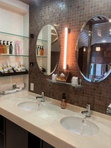 two sinks in a bathroom with two mirrors at Hulamoon in Maizuru