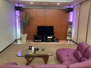a living room with a purple couch and a table at Hulamoon in Maizuru